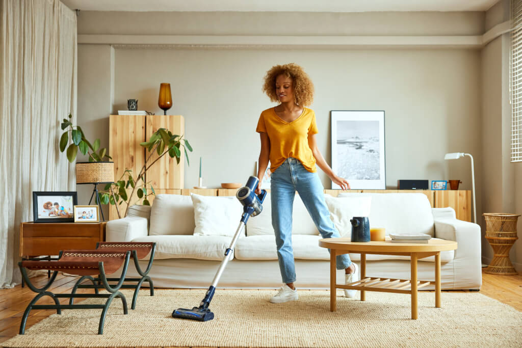 Woman cleaning carpet with vacuum cleaner at home