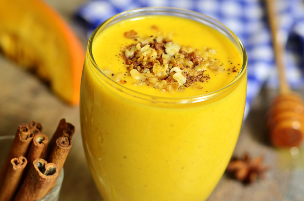 Homemade spicy pumpkin milkshake on rustic background.