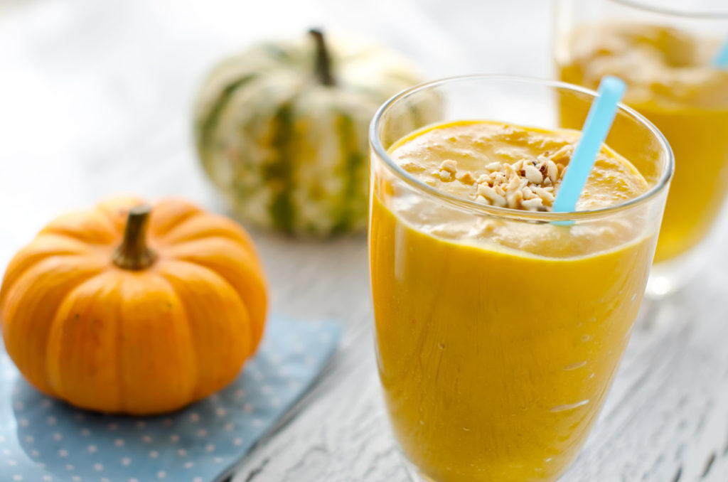 Beverage with pumpkins and milk wooden background