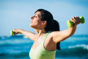 Fitness woman on workout. Motivated girl working out with dumbbells outdoor.