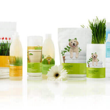 A lineup of pet grooming products with dog-themed packaging, arranged on a white surface with small plants and flowers.