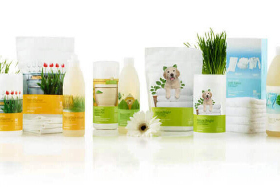 A lineup of pet grooming products with dog-themed packaging, arranged on a white surface with small plants and flowers.
