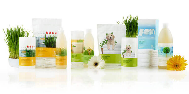 A lineup of pet grooming products with dog-themed packaging, arranged on a white surface with small plants and flowers.