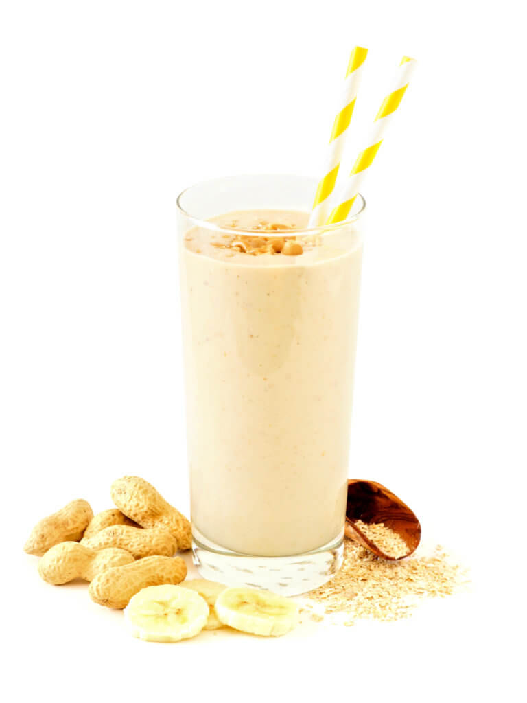 Peanutbutter banana oat smoothie with scattered ingredients over white